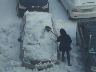 Девушка счищает снег с автомобиля... металлической лопатой